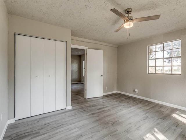 unfurnished bedroom with a textured ceiling, light hardwood / wood-style floors, a closet, and ceiling fan