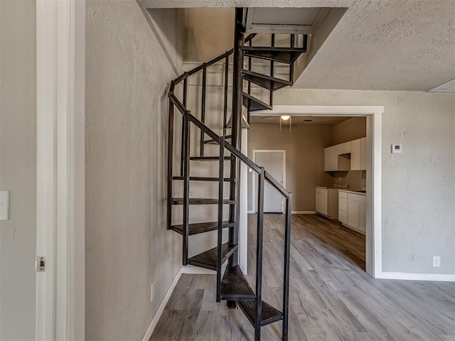 stairs featuring hardwood / wood-style floors and a textured ceiling