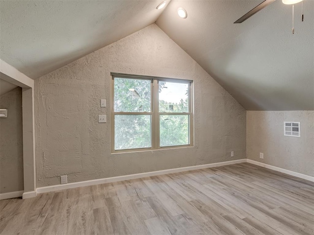 additional living space featuring ceiling fan, light hardwood / wood-style floors, a textured ceiling, and vaulted ceiling