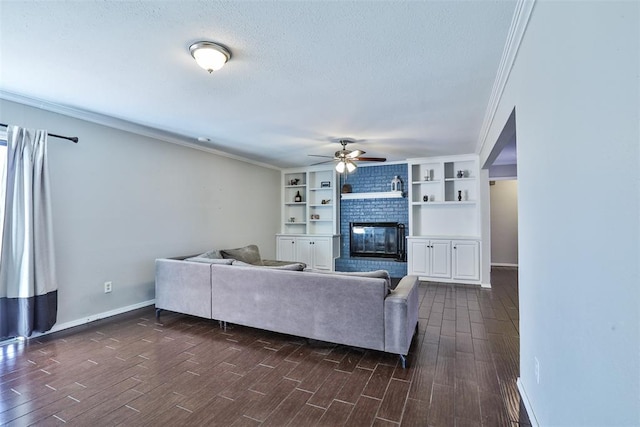 living room featuring dark wood-type flooring, a brick fireplace, ceiling fan, ornamental molding, and a textured ceiling