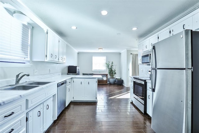 kitchen featuring sink, stainless steel appliances, dark hardwood / wood-style flooring, kitchen peninsula, and white cabinets