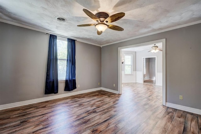 empty room with a textured ceiling, hardwood / wood-style flooring, ceiling fan, and crown molding