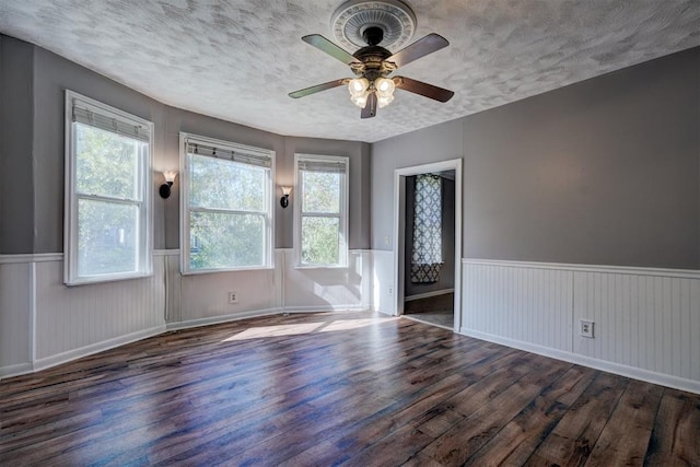 unfurnished room with ceiling fan, dark hardwood / wood-style flooring, and a textured ceiling