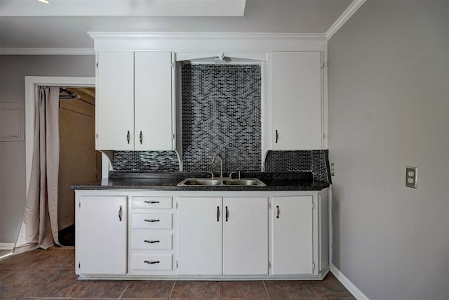 kitchen with backsplash, white cabinetry, sink, and ornamental molding