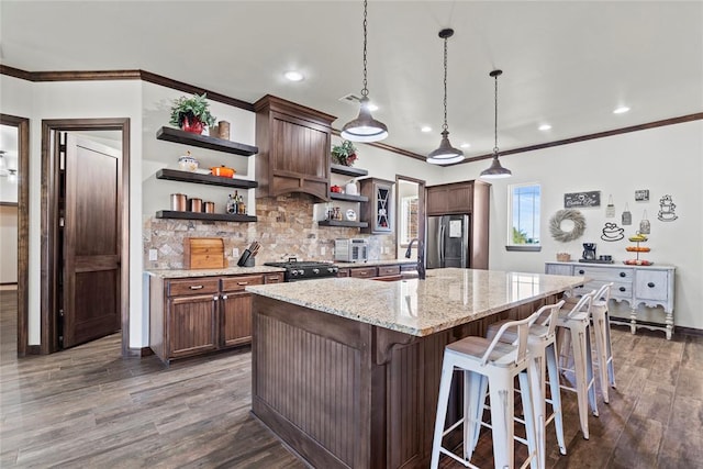 kitchen with dark wood-type flooring, a kitchen breakfast bar, decorative light fixtures, light stone counters, and stainless steel appliances