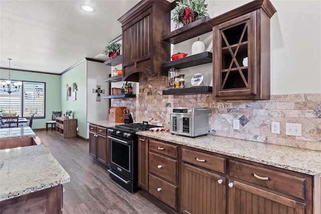 kitchen featuring gas range, light stone countertops, dark wood-type flooring, decorative light fixtures, and ornamental molding