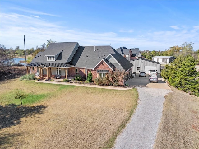 view of front of house with a garage, covered porch, an outdoor structure, and a front yard