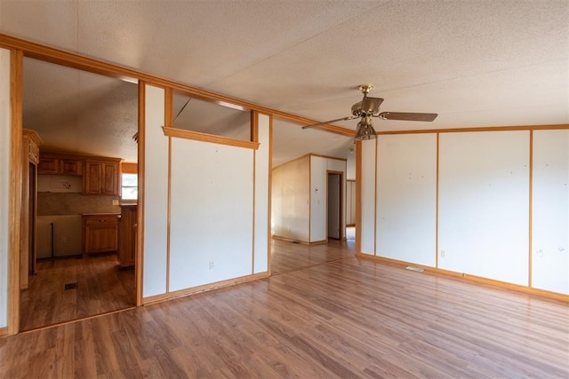 empty room with vaulted ceiling, ceiling fan, light hardwood / wood-style flooring, and a textured ceiling