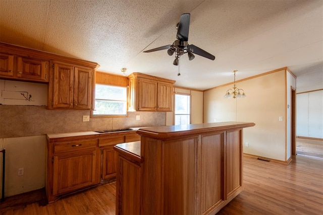 kitchen featuring light hardwood / wood-style flooring, a kitchen island, pendant lighting, and ceiling fan with notable chandelier