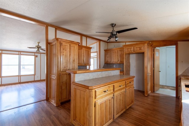 kitchen with ceiling fan, a center island, wood-type flooring, and a textured ceiling