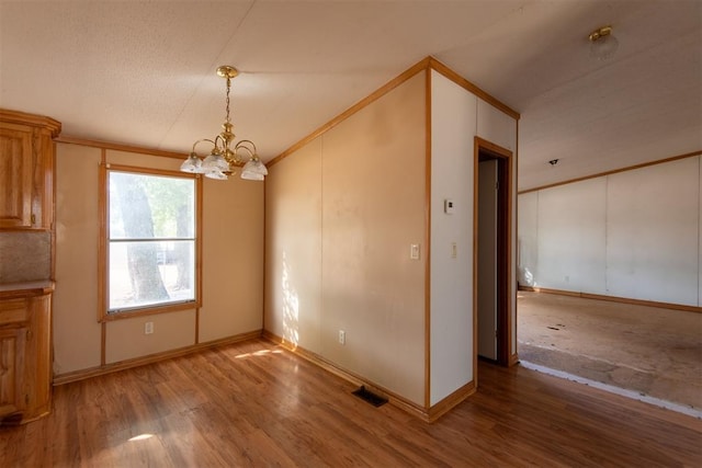 unfurnished dining area with hardwood / wood-style floors, a notable chandelier, and crown molding