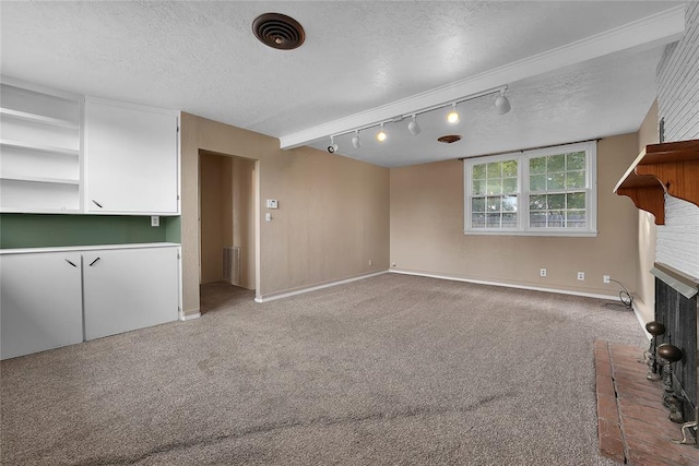 unfurnished living room featuring track lighting, light colored carpet, a textured ceiling, and a brick fireplace