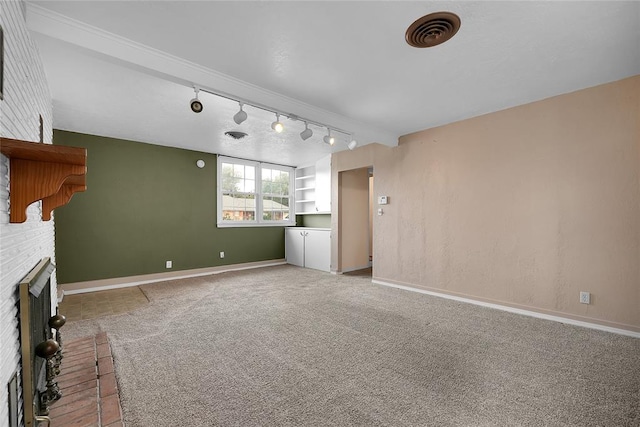 unfurnished living room with carpet flooring, a fireplace, and track lighting