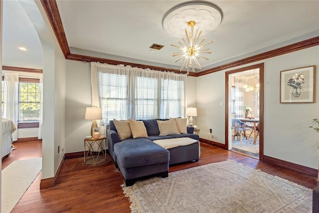 living room with hardwood / wood-style flooring, crown molding, and a chandelier