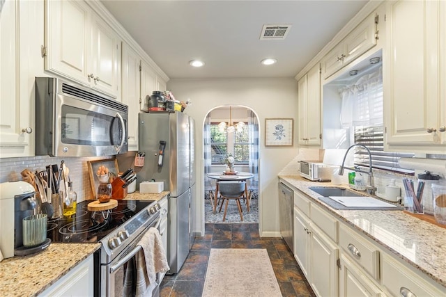 kitchen featuring stainless steel appliances, tasteful backsplash, light stone countertops, and sink