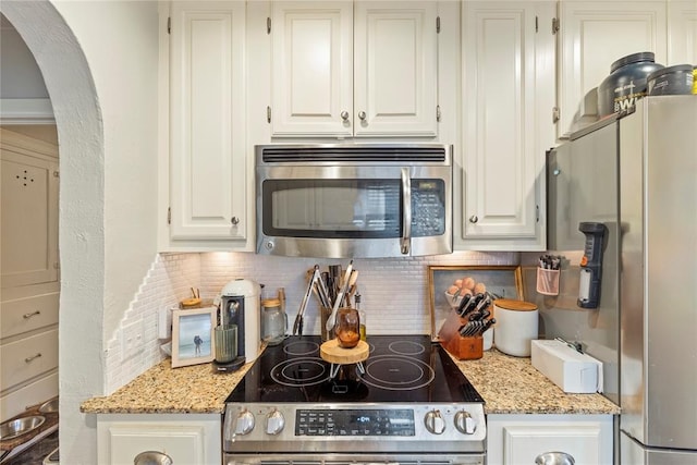 kitchen featuring tasteful backsplash, light stone countertops, appliances with stainless steel finishes, and white cabinets