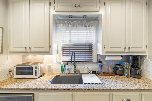 kitchen with a toaster, white cabinetry, a sink, and white dishwasher