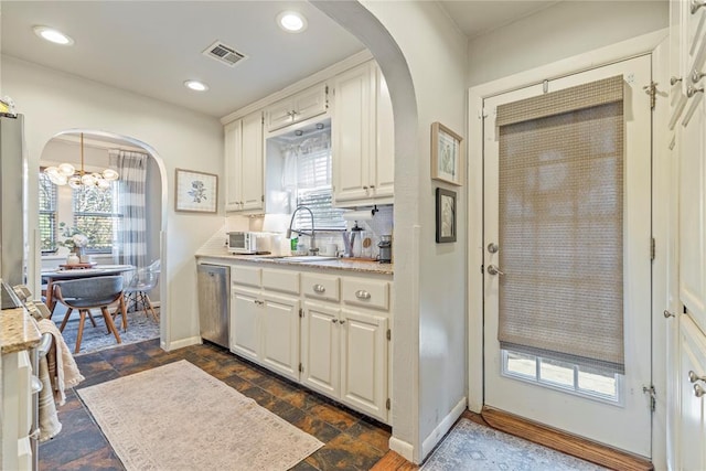 kitchen with arched walkways, light countertops, and dishwasher