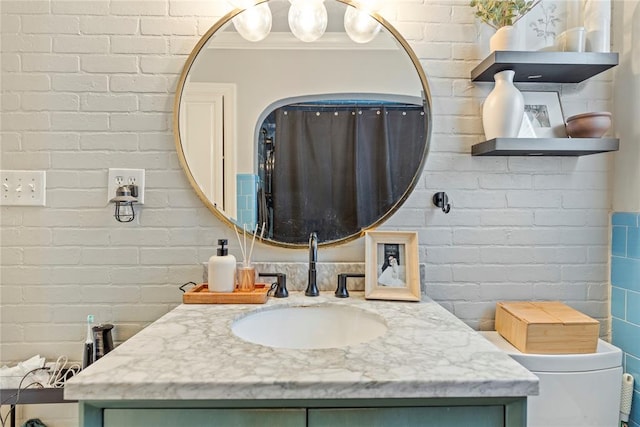 bathroom featuring vanity, brick wall, crown molding, and toilet