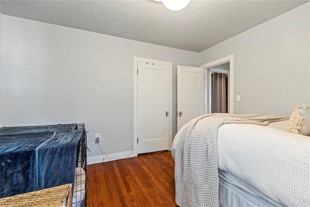 bedroom with dark wood-style floors, a textured ceiling, and baseboards