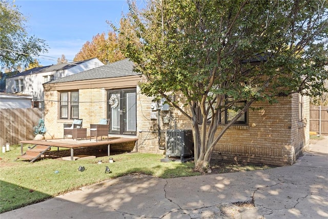 rear view of property with brick siding, fence, and central air condition unit