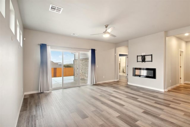 2200 El Cajon St, Edmond, OK 73034 - unfurnished living room with wood finished floors, a ceiling fan, and a glass covered fireplace