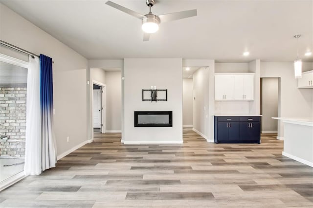 2200 El Cajon St, Edmond, OK 73034 - unfurnished living room featuring a ceiling fan, light wood-style flooring, a glass covered fireplace, and recessed lighting