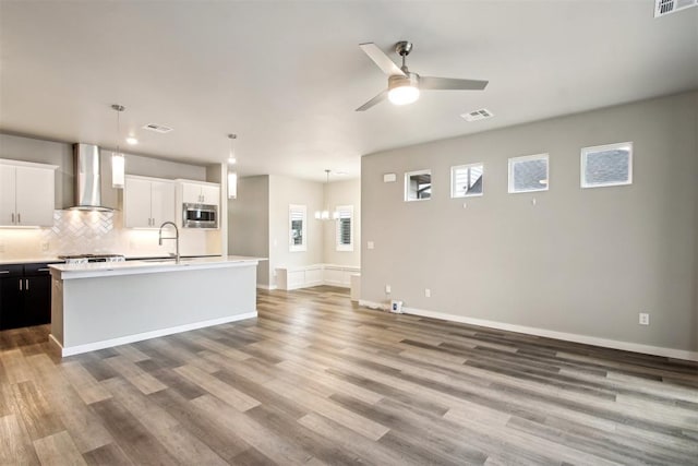 2200 El Cajon St, Edmond, OK 73034 - kitchen with wall chimney exhaust hood, stainless steel microwave, light countertops, and light wood-type flooring