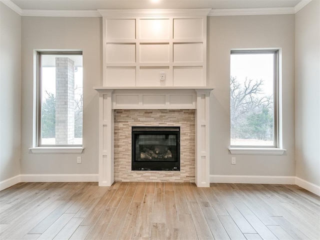 unfurnished living room with plenty of natural light, ornamental molding, a fireplace, and light hardwood / wood-style flooring