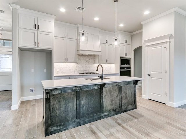 kitchen featuring pendant lighting, white cabinetry, an island with sink, and stainless steel appliances