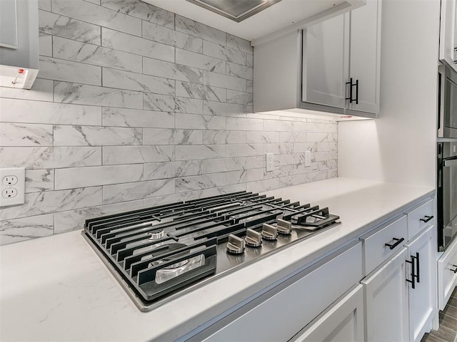 kitchen featuring wall oven, stainless steel gas stovetop, white cabinetry, and tasteful backsplash