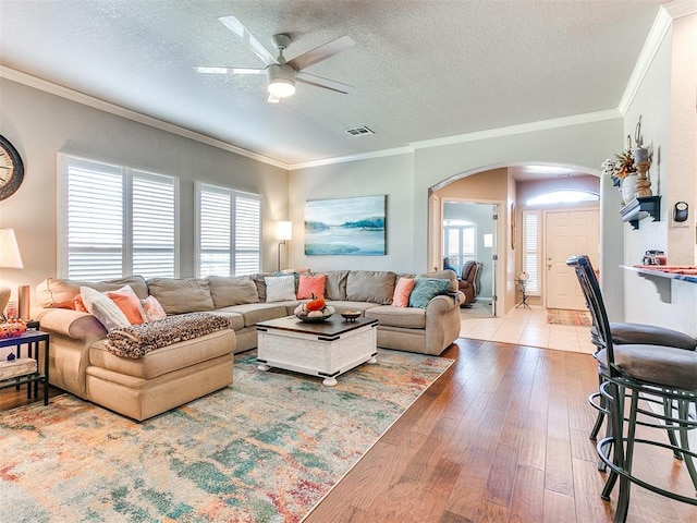 living room with ornamental molding, wood-type flooring, and a textured ceiling