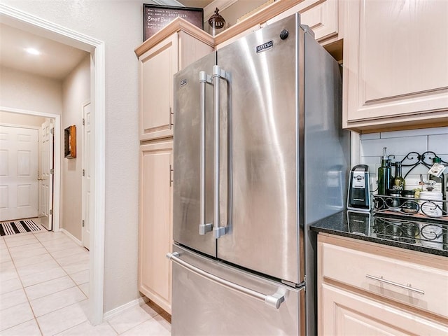 kitchen with dark stone countertops, backsplash, high end refrigerator, and light tile patterned flooring