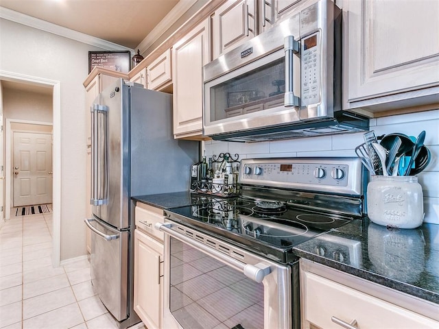 kitchen featuring dark stone countertops, light tile patterned floors, crown molding, and appliances with stainless steel finishes