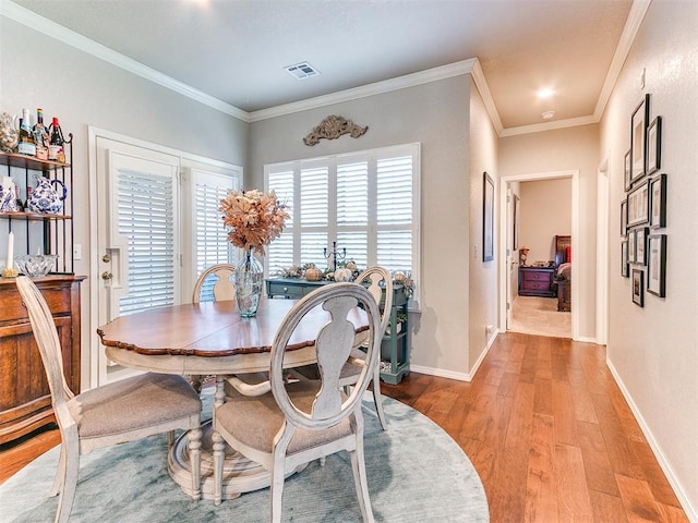 dining room featuring ornamental molding, a healthy amount of sunlight, and light hardwood / wood-style flooring