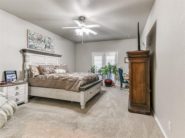 bedroom with ceiling fan, light colored carpet, and a textured ceiling