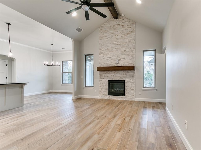 unfurnished living room with a fireplace, beamed ceiling, light wood-type flooring, and a healthy amount of sunlight