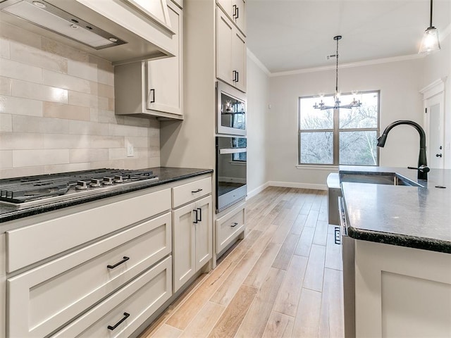 kitchen featuring pendant lighting, exhaust hood, ornamental molding, tasteful backsplash, and stainless steel gas cooktop