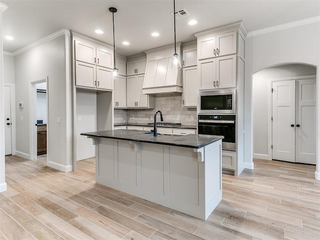 kitchen featuring stainless steel appliances, backsplash, crown molding, an island with sink, and pendant lighting