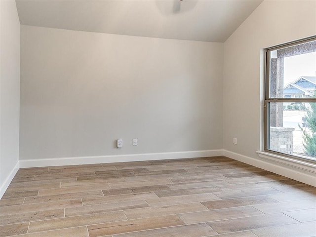 spare room featuring light hardwood / wood-style flooring and lofted ceiling