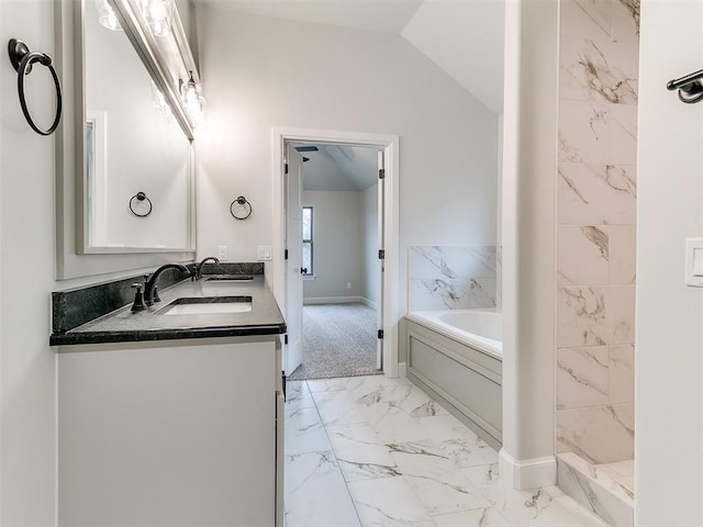 bathroom with a washtub, vanity, and vaulted ceiling