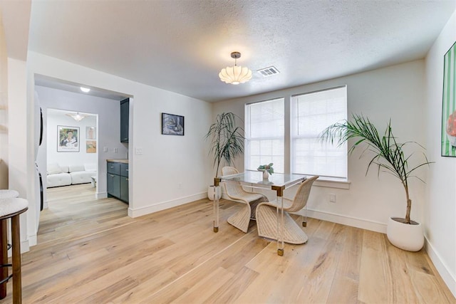 dining room featuring a textured ceiling and light wood-type flooring