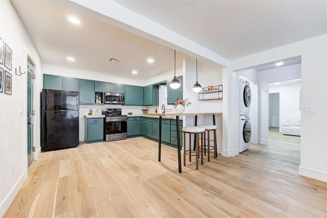 kitchen with a breakfast bar, stacked washer / dryer, decorative light fixtures, light hardwood / wood-style flooring, and stainless steel appliances