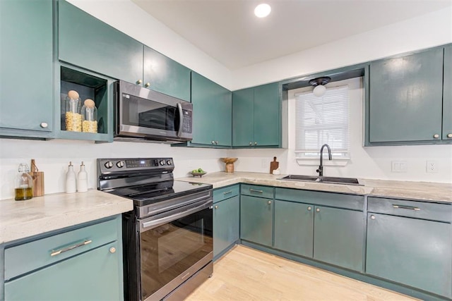 kitchen featuring stainless steel appliances, sink, light stone counters, and light hardwood / wood-style flooring