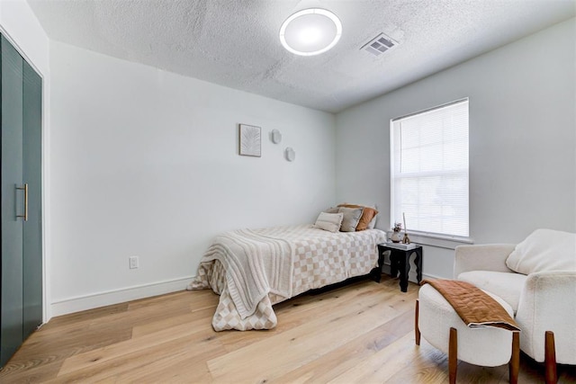 bedroom with hardwood / wood-style floors and a textured ceiling