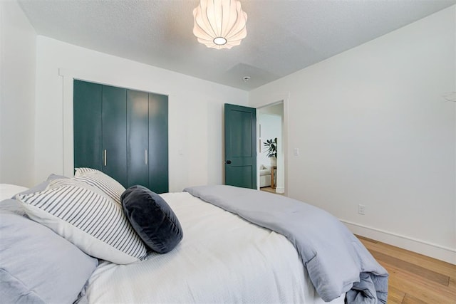 bedroom with light hardwood / wood-style flooring, a textured ceiling, and a closet