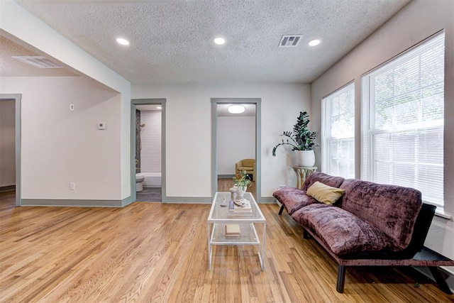 living room with a textured ceiling and light hardwood / wood-style floors