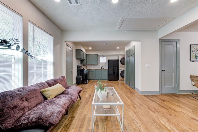 living room with stacked washer and dryer, a wealth of natural light, and light hardwood / wood-style floors