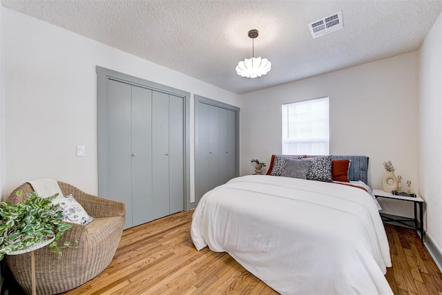 bedroom with hardwood / wood-style flooring, a textured ceiling, and two closets