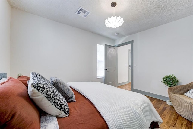 bedroom with a textured ceiling and light wood-type flooring